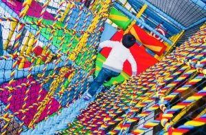 Child climbing through a colourful rope tunnel